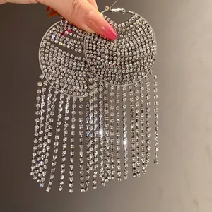 Hand holding elegant silver rhinestone hoop earrings with long shimmering tassels details
