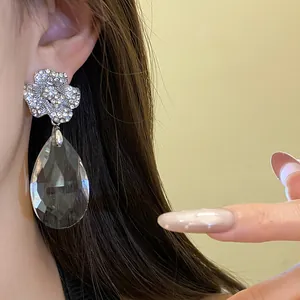 Détail en gros plan de boucles d'oreilles fleur en strass et pendentif goutte d'eau