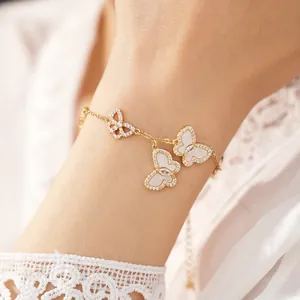 Nahaufnahme eines eleganten Goldarmbands mit weißen Schmetterlingen und Zirkonia