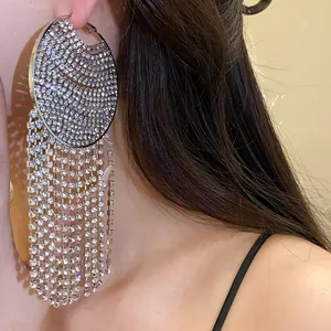 Close-up of sparkling rhinestone circular hoop earrings with long tassels shown on a model