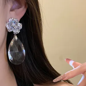 Gros plan détaillé de boucles d'oreilles fleur strass avec pendentif cristal élégant.