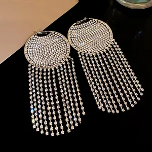 Close-up of elegant silver needle hoop earrings featuring long rhinestone tassels