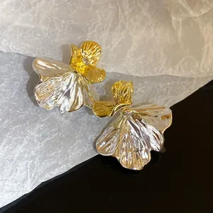 Dettaglio ravvicinato di orecchini a fiore bicolore materici con diamante centrale