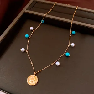 Detail view of 18K gold plated necklace featuring white pearls and turquoise beads