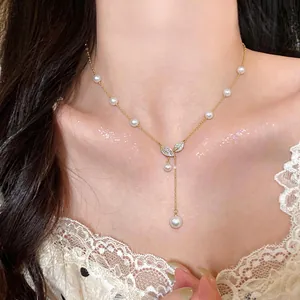 Détail d'un élégant collier en perles et feuilles plaqué or 18 carats porté au cou.