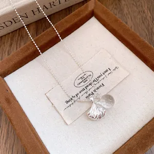 Primo piano di una collana a conchiglia d'argento con sfera in resina e strass