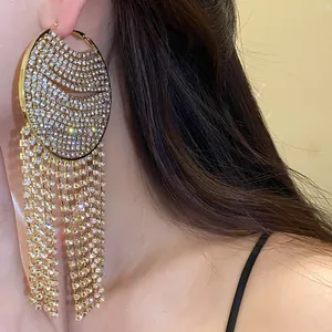 Close-up detail of large luxury round rhinestone tassel dangle earrings on a model ear.