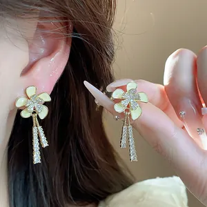 Primer plano de pendientes de flores bañados en oro 18k con borlas de circonitas.