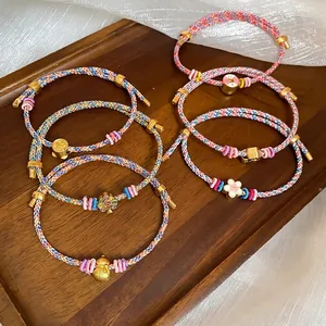 Handmade colorful braided bracelets with gold gourd and flower charms on a wooden tray