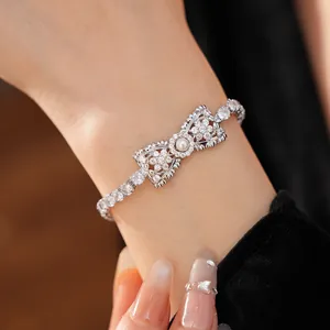 Elegante zilveren strikarmband met zirkonia en pareldetails om een vrouwelijke pols