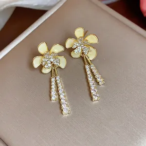 Primer plano de elegantes pendientes de flores bañados en oro 18k con circonitas