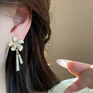 Vista detallada de elegantes pendientes de flor de circonita bañados en oro de 18k en modelo.