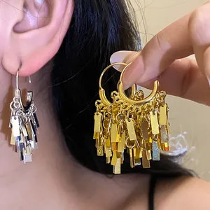 Close-up detail of geometric metallic tassel pendant earrings in gold and silver finish
