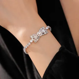 Detailopname van zilveren strikarmband met zirkonia en centrale parelaccent