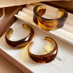 Primo piano di tre bracciali rigidi geometrici in acrilico ambrato in una scatola