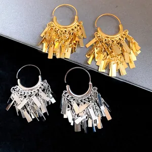 Detailed macro view of gold and silver metallic geometric tassel drop hoop earrings