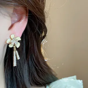 Primer plano de elegantes pendientes de flores bañados en oro de 18k con borlas de circón