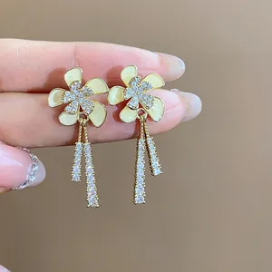 Primer plano de elegantes pendientes de flores chapados en oro de 18k con borlas de circón