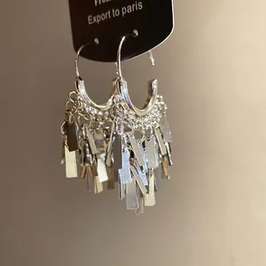 Detail view of silver metallic geometric tassel earrings with rectangular pendants.