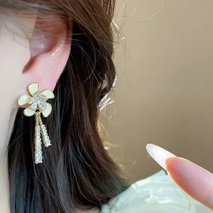 Primer plano de elegantes pendientes de flor bañados en oro de 18k con circonitas