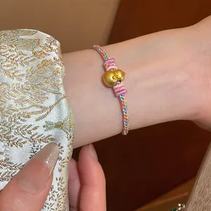 Detailed view of hand-woven braided bracelet with golden gourd pendant and floral accents