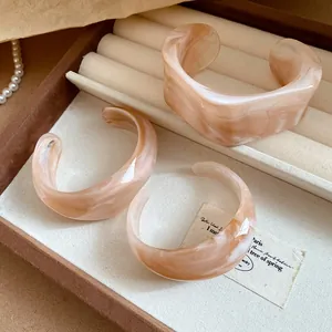 Dettaglio di tre bracciali geometrici in acrilico marmorizzato in un portagioie elegante