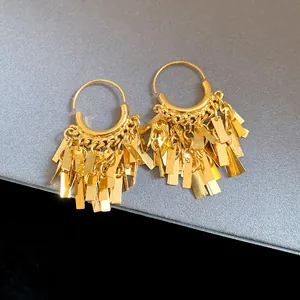 Detailed view of gold geometric tassel drop earrings with polished metallic finish