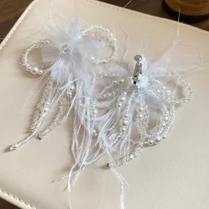 Elegante set di gioielli con fiori di piume bianche e perle per un look romantico.