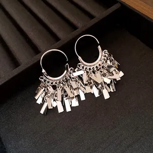Macro detail shot of silver geometric fringe pendant earrings on a black jewelry tray.