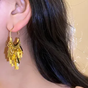 Close-up detail of golden geometric tassel drop earrings on model for a chic metal look