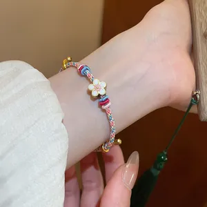 Hand-woven colorful braided bracelet with a delicate pink and white flower charm