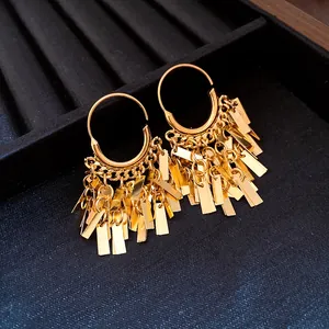Macro detail of golden geometric fringe tassel hoop earrings on black velvet jewelry tray