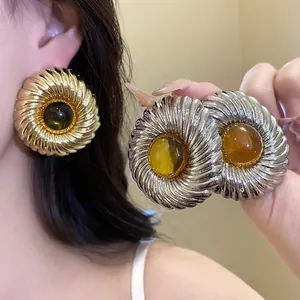 Detailed view of large circular textured stud earrings featuring an amber resin center