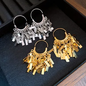 Close-up of gold and silver metallic geometric tassel earrings in a display tray.