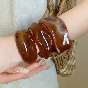 Primo piano di bracciali geometrici in acrilico marmorizzato con finitura ambra