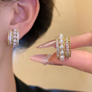 Elegante 14k vergoldete Ohrclips mit weißen Perlen und funkelnden Zirkoniasteinen.