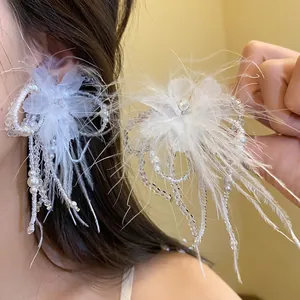 Primo piano di orecchini di piume bianche con perle di vetro e dettagli floreali