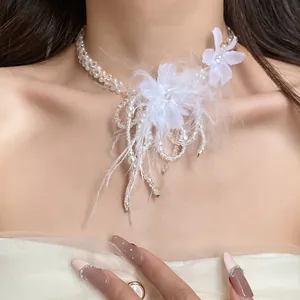 Dettaglio ravvicinato di collana con piume bianche, fiori e perle di vetro fini