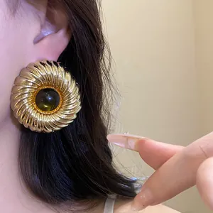 Close-up detail of golden sunburst textured earring with dark amber resin center