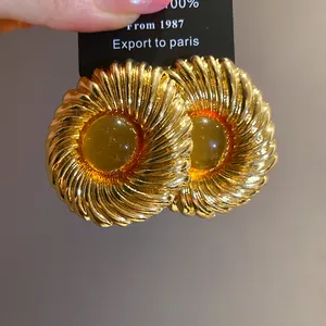 Close-up of vintage textured gold stud earrings with amber resin center.
