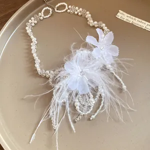 Primo piano dettagliato di un'elegante collana con piume bianche, fiori e perle