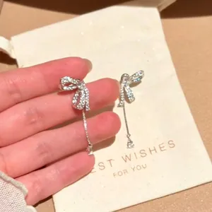 Detailed close-up of sparkling zircon bow earrings featuring elegant water drop tassels.