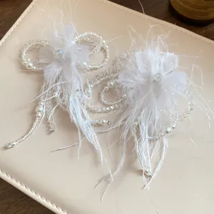 Dettaglio di eleganti accessori floreali in piume bianche con perle e cristallo