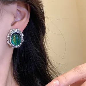 Dettaglio di orecchino a perno vintage in resina verde con cornice di strass luminosa