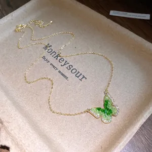 Dainty gold necklace featuring a sparkling green crystal butterfly pendant for women