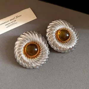 Close-up of vintage silver spiral textured stud earrings with an amber resin center piece