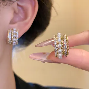 Nahaufnahme eleganter vergoldeter Ohrclips mit Perlen und funkelnden Zirkonen