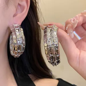Primer plano de pendientes de aro en forma de C texturizados plateados con acabado rugoso.