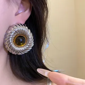 Macro detail view of a silver textured round stud earring with a resin center.