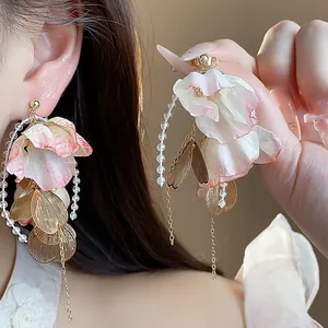 Close-up of elegant acrylic flower petal earrings with gold leaf and pearl details